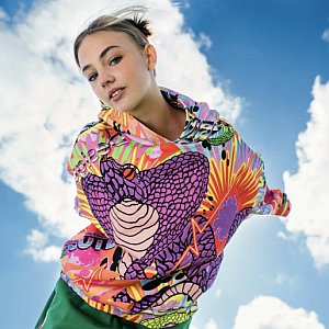 Girl wearing colourful jacket with a sky background, looks like she is flying